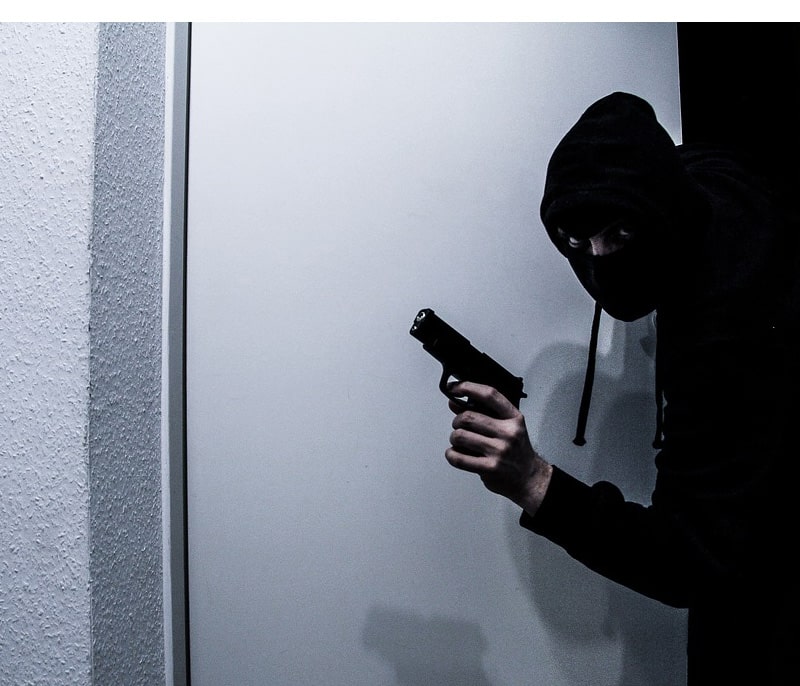 A masked burglar, armed with a pistol and invading a home.